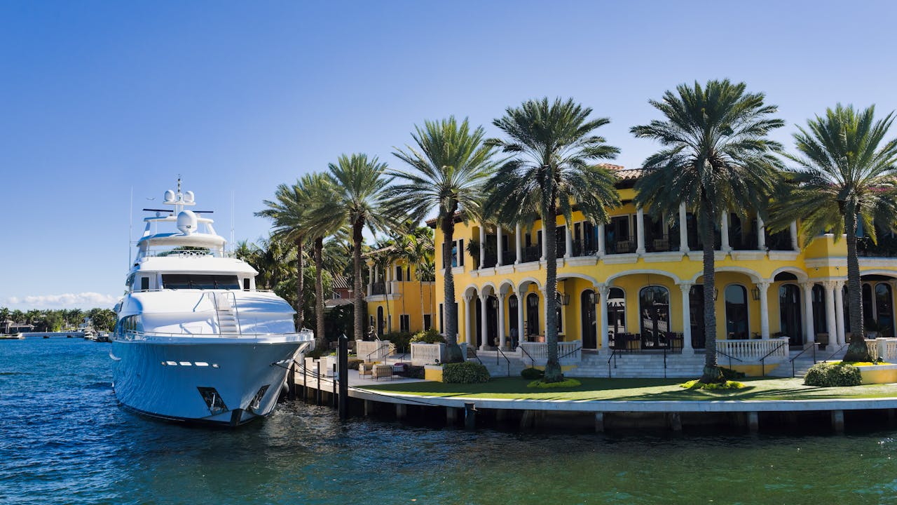 A stunning view of a luxury yacht docked beside a grand mansion in Fort Lauderdale, Florida.